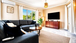 A modern living room with a sofa, coffee table, TV, and a potted plant.