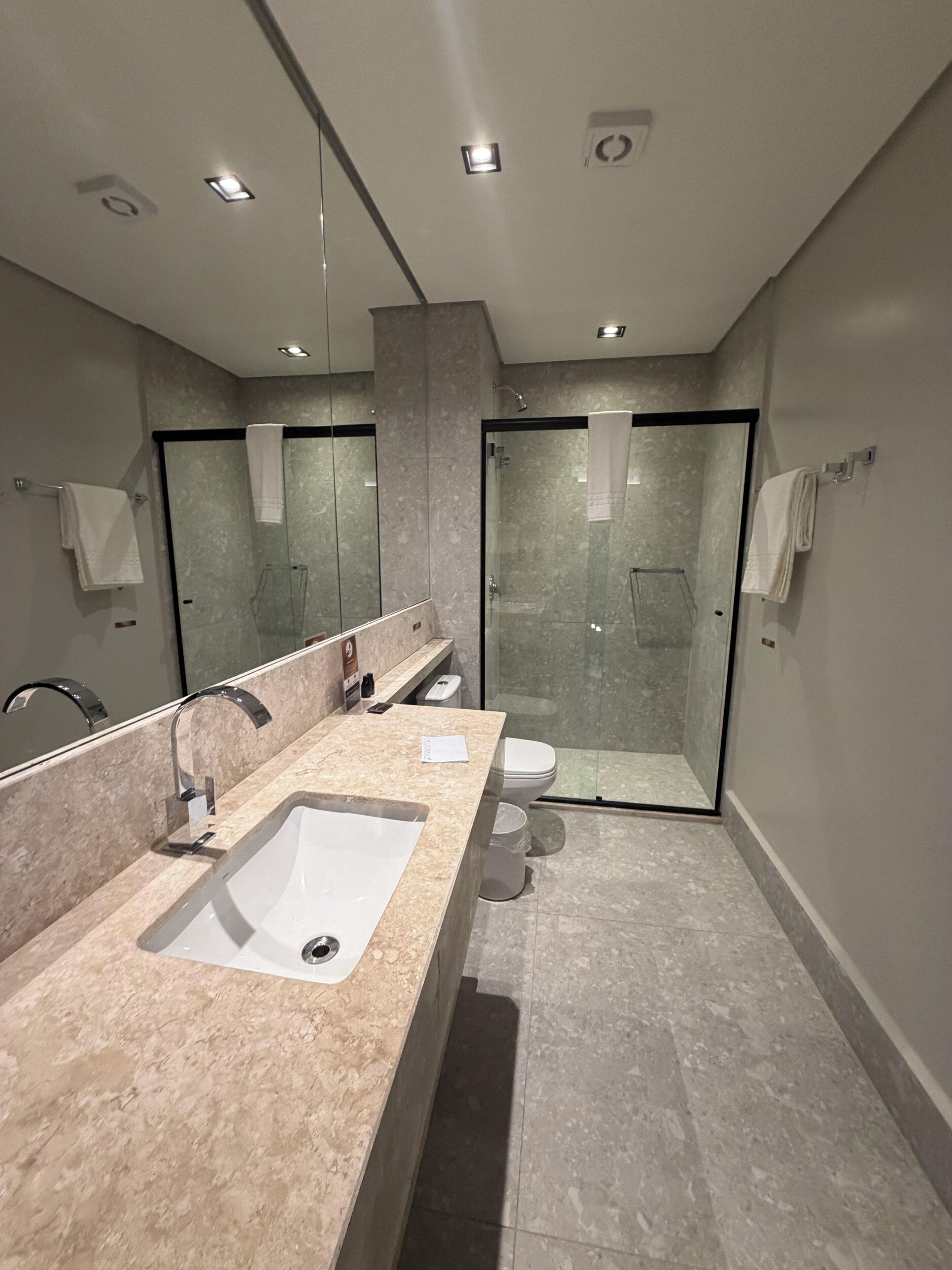 Un baño moderno con un lavamanos grande, cabina de ducha con mampara de vidrio y un inodoro.