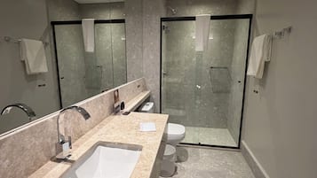 Un baño moderno con un lavamanos grande, cabina de ducha con mampara de vidrio y un inodoro.