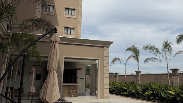 A hotel with a swimming pool, outdoor seating, and palm trees. - Class Hotel Americana (Americana)