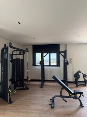 A gym with various exercise equipment, a window with a view, and a sign on the wall.