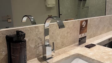 Um banheiro moderno com pia branca, espelho, porta-toalhas e máquina de café.