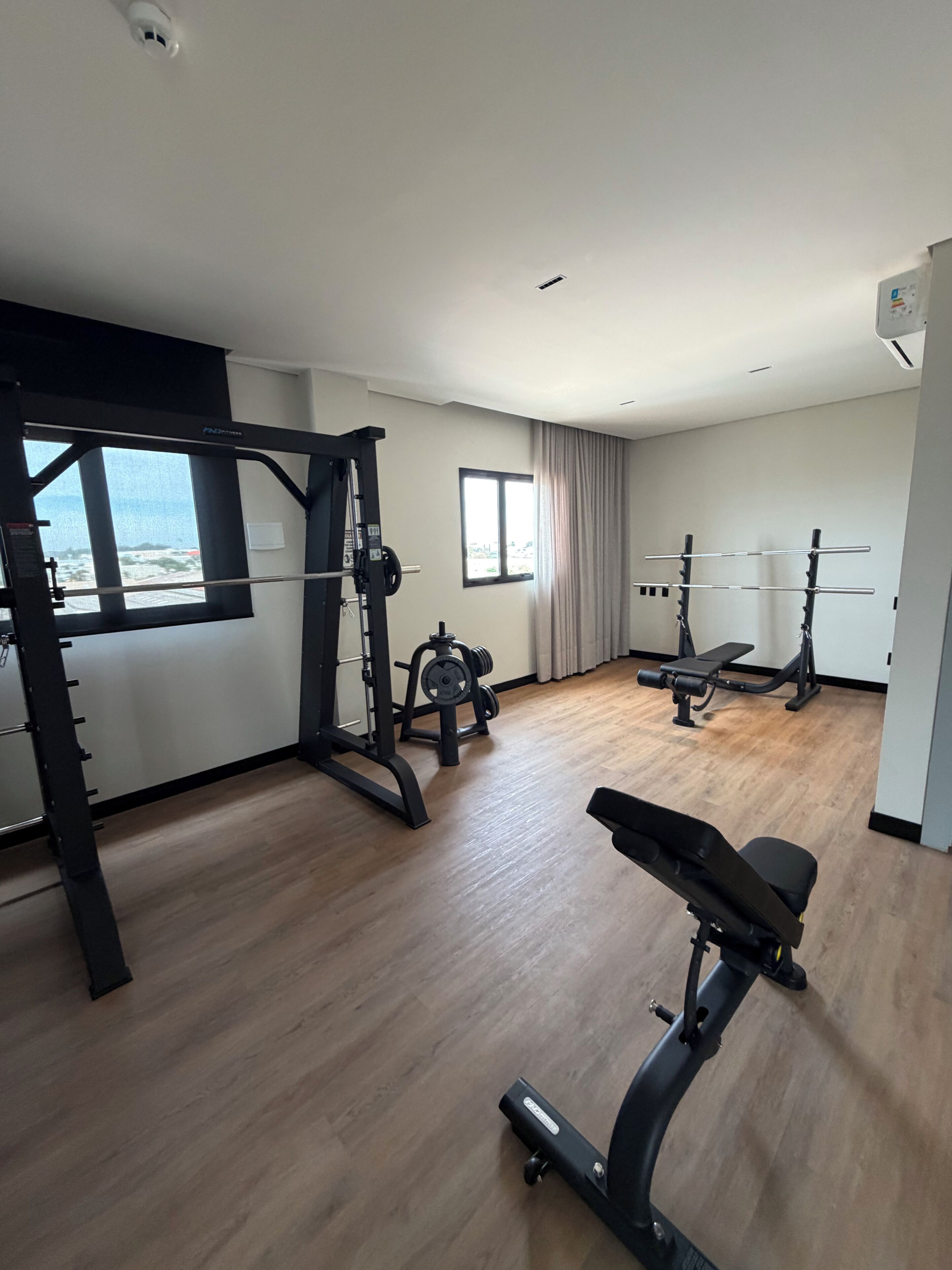 A gym with a variety of equipment including a squat rack, bench press, and dumbbells.