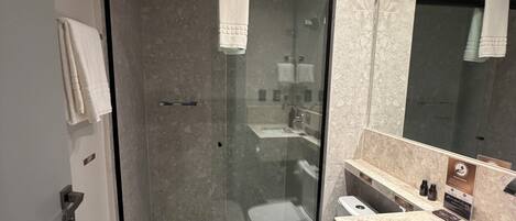 A modern bathroom with a glass-enclosed shower, a white toilet, and a marble countertop.