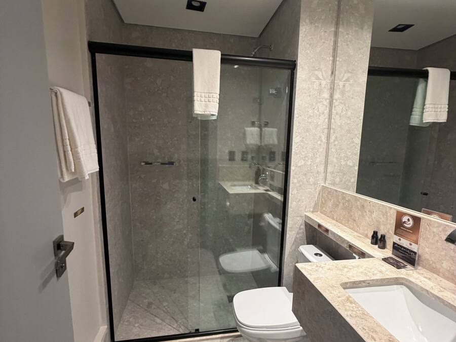 A modern bathroom with a glass-enclosed shower, a white toilet, and a marble countertop.