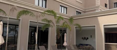 A hotel with a swimming pool, lounge chairs, and palm trees.
