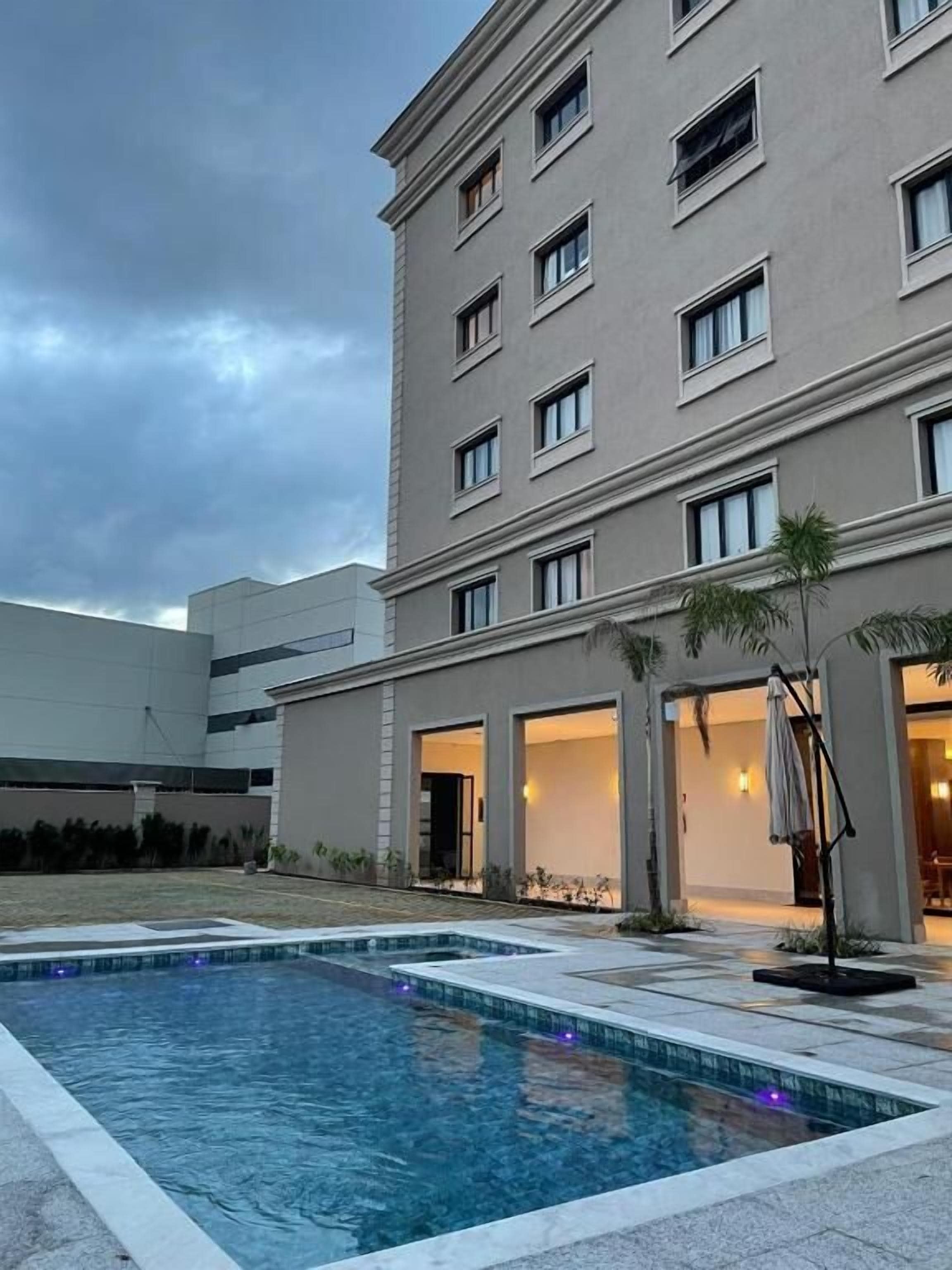 Um hotel com piscina, área de estar externa e fachada com várias janelas.
