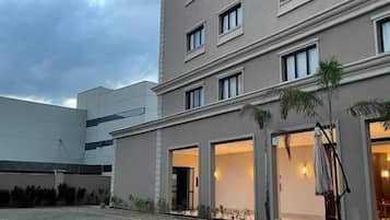 Um hotel com piscina, área de estar externa e fachada com várias janelas.