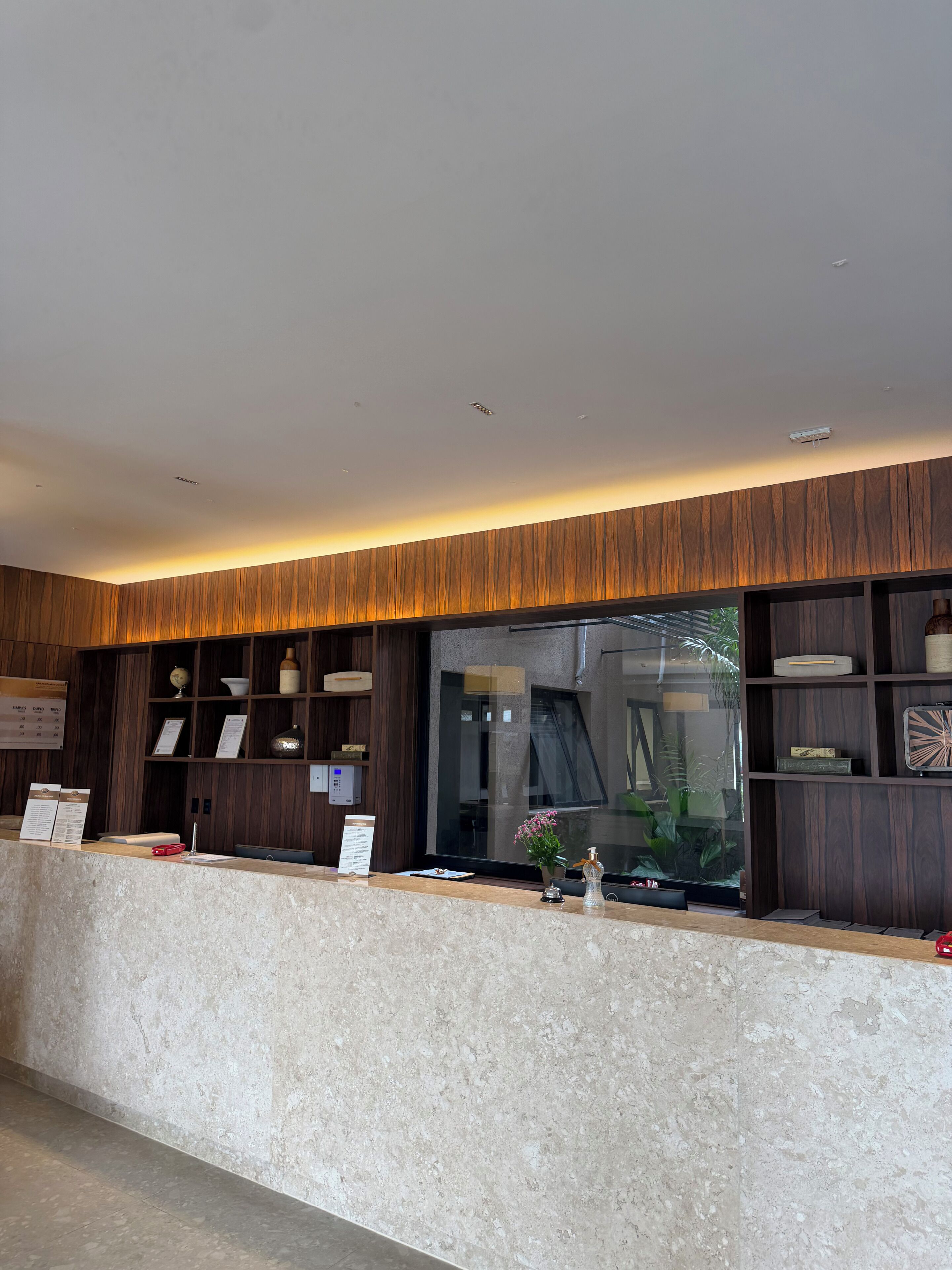 Una recepción con un diseño de paneles de madera, un ventanal y vistas a plantas de interior.