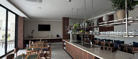 Un restaurante moderno con una barra larga, sillas de madera y una variedad de plantas.