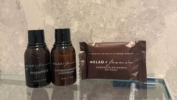 Zwei Shampoo- und zwei Conditionerflaschen sowie eine Seifenpackung auf einer Glasplatte.