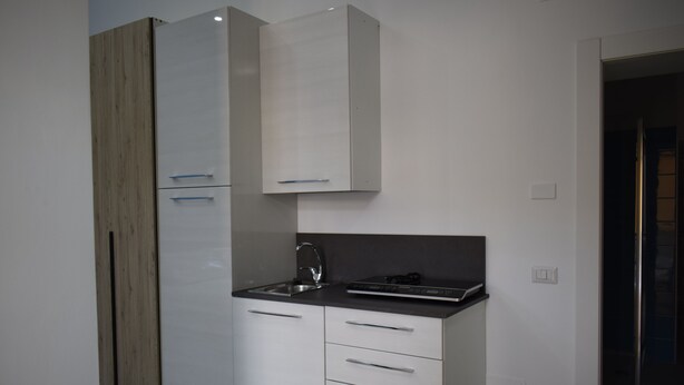 Una cocina moderna con armarios blancos, un lavamanos de acero inoxidable y una encimera negra.