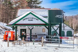 Une gare de style rustique, avec une enseigne indiquant « Huntsville & Lake of Bays Railway », une plateforme tournante et un réservoir d’eau.