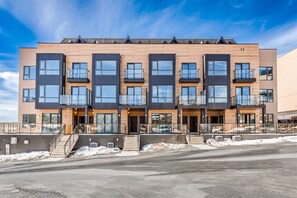 A modern multi-story residential building with balconies, large windows, and a brick facade. - Modern Townhome with Fairy Lake Views Near Downtown Huntsville (Huntsville)