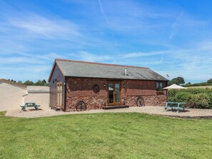 A rustic building with a brick exterior, a pitched roof, and a small porch. - Little Owl Barn (Wellington)
