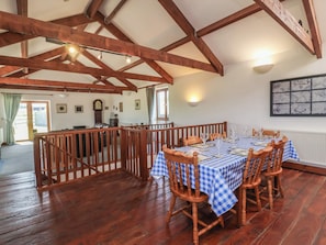 A dining area with a checkered tablecloth, wooden chairs, and a high ceiling with exposed beams. - Little Owl Barn (Wellington)