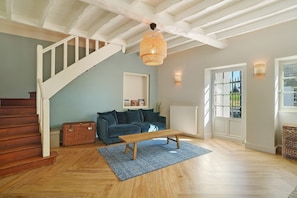 A staircase leading to a landing with a wicker bench and a blue rug.