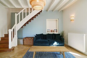 A staircase with white railings, a dark blue sofa, a wooden coffee table, and a wicker lamp.