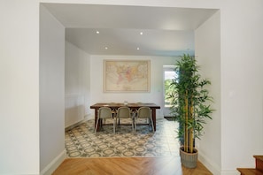 Un comedor con una mesa y sillas de madera, un gran mapa mundial en la pared y una planta en maceta.