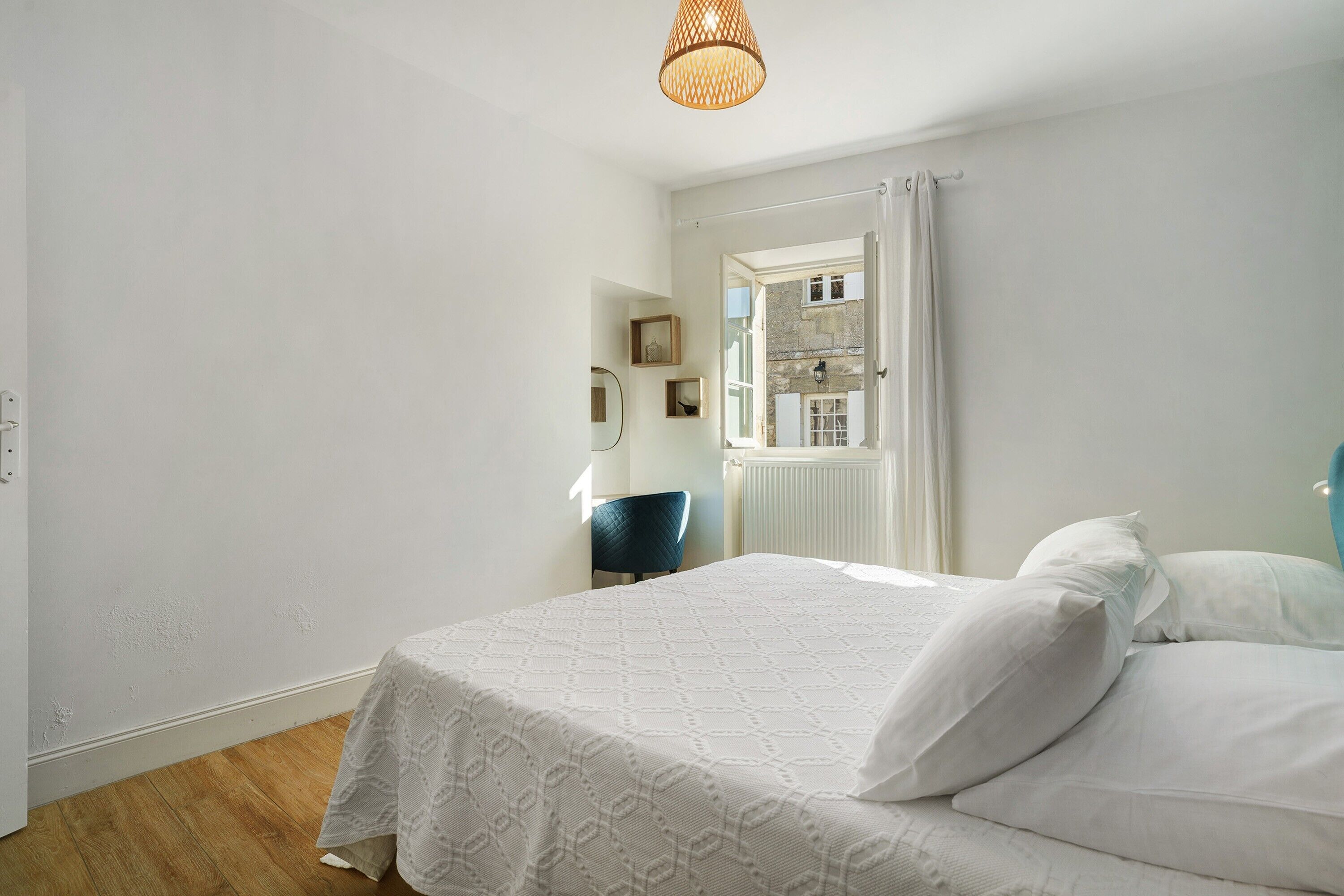 Un dormitorio con cama, una silla, una ventana y una puerta que da a un baño.