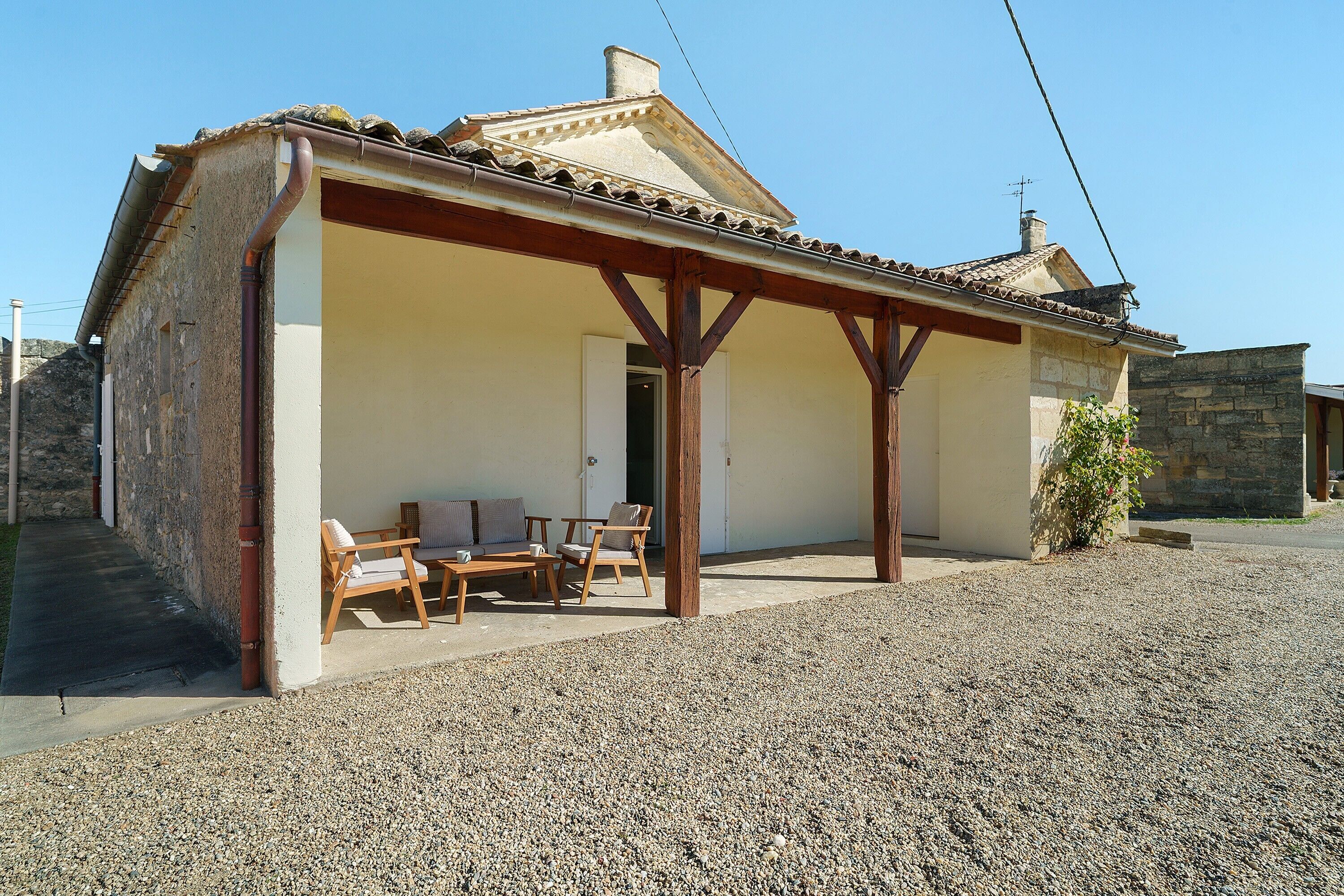 A building with a covered patio, outdoor seating, and a gravel ground.