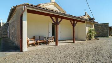 A building with a covered patio, outdoor seating, and a gravel ground.