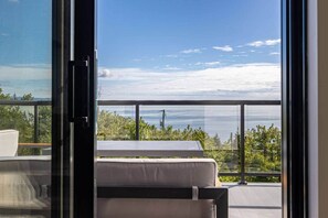 Ein Balkon mit Blick auf das Meer, ein weißes Sofa und ein Tisch.