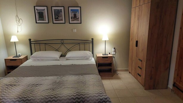 A bedroom with a bed, two bedside tables with lamps, a wardrobe, and three framed pictures on the wall. - Geronymos Stone Villa Pool Chania Apokoronas Crete (Fres)