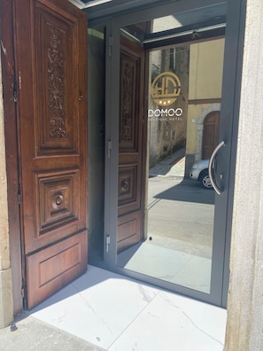 Entrada de hotel con puerta de vidrio, puerta de madera y un letrero que dice 'DOMO BOUTIQUE HOTEL'.