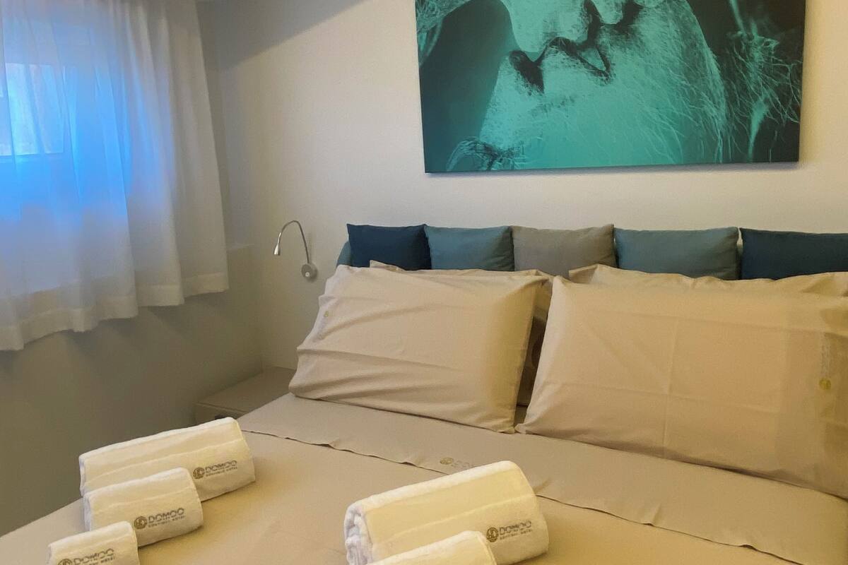 A hotel room with a bed, pillows, a wall-mounted artwork, and towels.