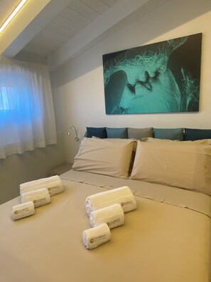 A hotel room with a bed, pillows, a wall-mounted artwork, and towels. - Domoo Boutique Hotel (Torraca)