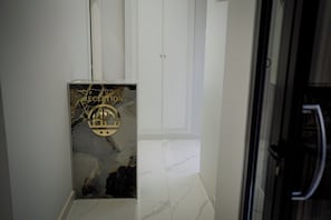 Un área de recepción con piso de mármol, una recepción con un emblema dorado y una puerta blanca al fondo.