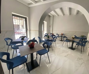 Un comedor con mesas y sillas, un amplio arco y vistas al exterior.