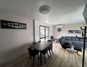 A modern living space with a dining area, a sofa, and a large window. - A beautiful, cozy, and functional apartment (Drancy)