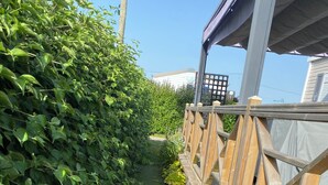 A pathway flanked by dense green foliage and a wooden fence. - Mobile home at a 2-star campground, a 10-minute walk from the beach (Saint-Cast-le-Guildo)