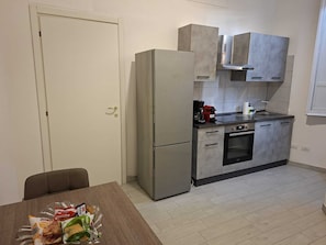 Kompakti keittiö, jossa on jääkaappi, uuni ja kahvinkeitin.