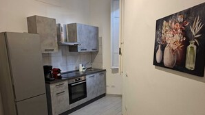 Una cucina moderna con mobili grigi, un frigorifero in acciaio inossidabile, un forno integrato e un lavello. Al muro, un quadro con fiori.