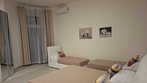 Camera d'albergo con due letti, un divano, uno specchio e due quadri appesi al muro.