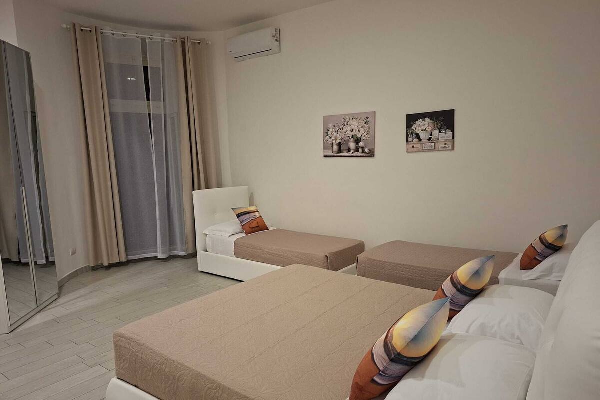 A hotel room with two beds, a sofa, a mirror, and two wall-mounted pictures.