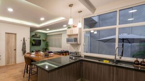 Une cuisine moderne dotée d’un îlot central, d’un four à micro-ondes encastré et d’une grande fenêtre agrémentée d’un parasol.