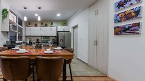 Une cuisine moderne avec des meubles blancs, une table à manger pour quatre personnes et un réfrigérateur.