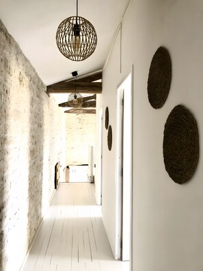 A hallway with exposed brick walls, a wooden floor, and a hanging light fixture. - Pressoir Gite - 3 beedroom Gite with Private terrace and shared pool (Saint-Mandé-sur-Brédoire)