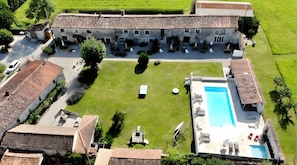 Un edificio grande con piscina, varias habitaciones y un césped bien cuidado.