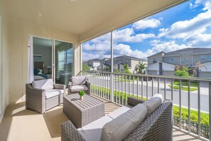 A balcony with wicker furniture, a sliding glass door, and a view of neighboring houses. - AEA - Davenport FL  (Kissimmee)