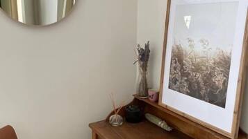 Een houten bureau met een lijstfoto, een spiegel en een stoel.