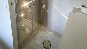 Un baño con cabina de ducha de vidrio, un espejo y un inodoro.