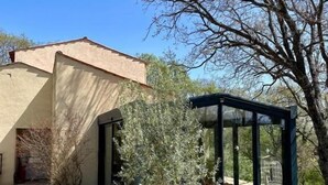Una casa con patio, cerramiento de vidrio y un árbol.