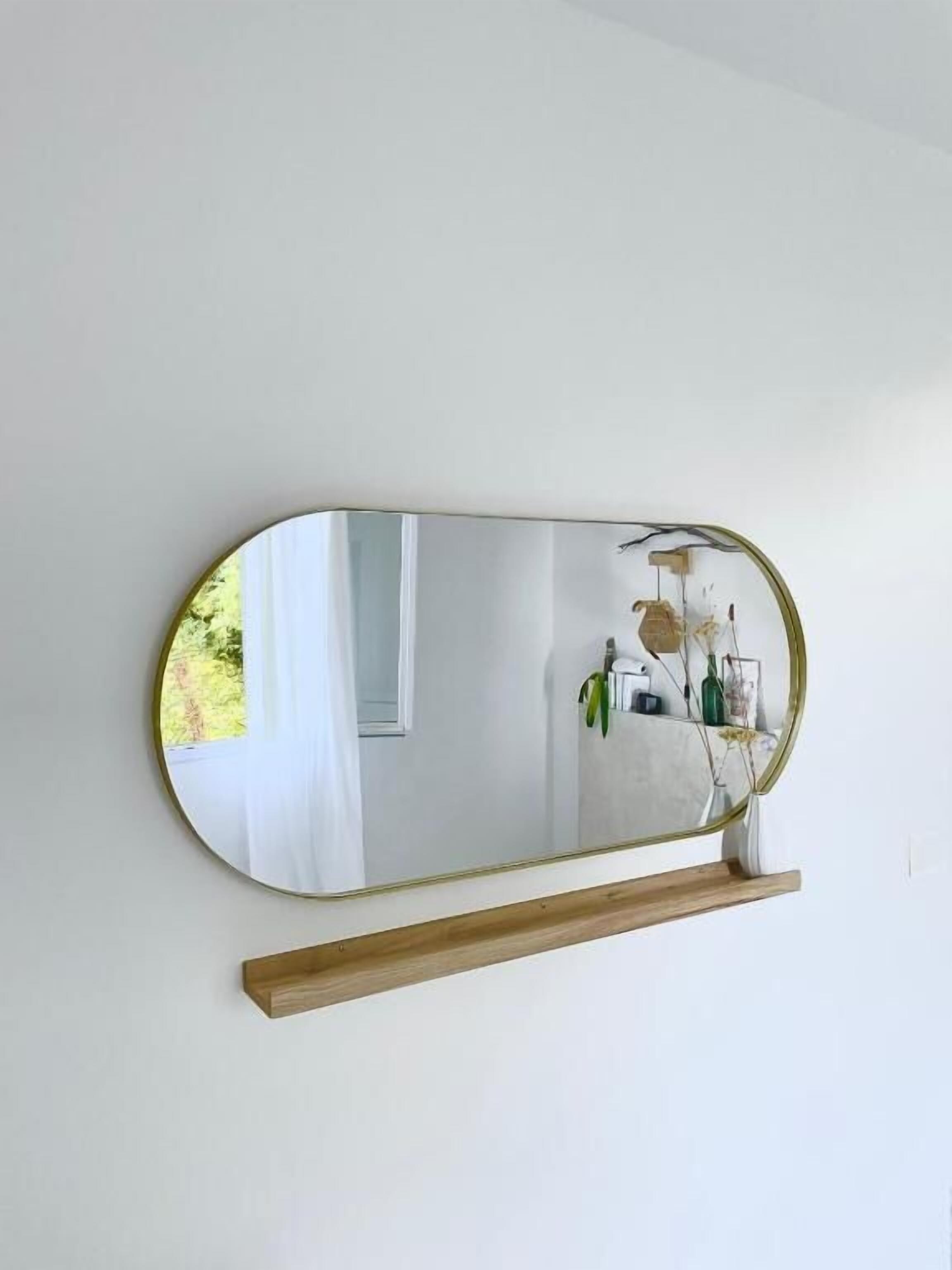 A wall-mounted mirror with a wooden shelf below it.