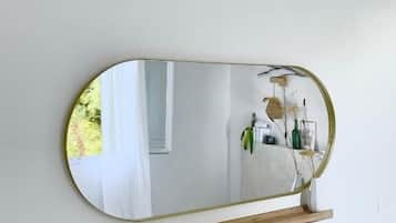 A wall-mounted mirror with a wooden shelf below it.