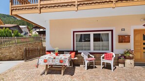 Un espacio exterior acogedor con una mesa y sillas, un balcón de madera y una pared de piedra.